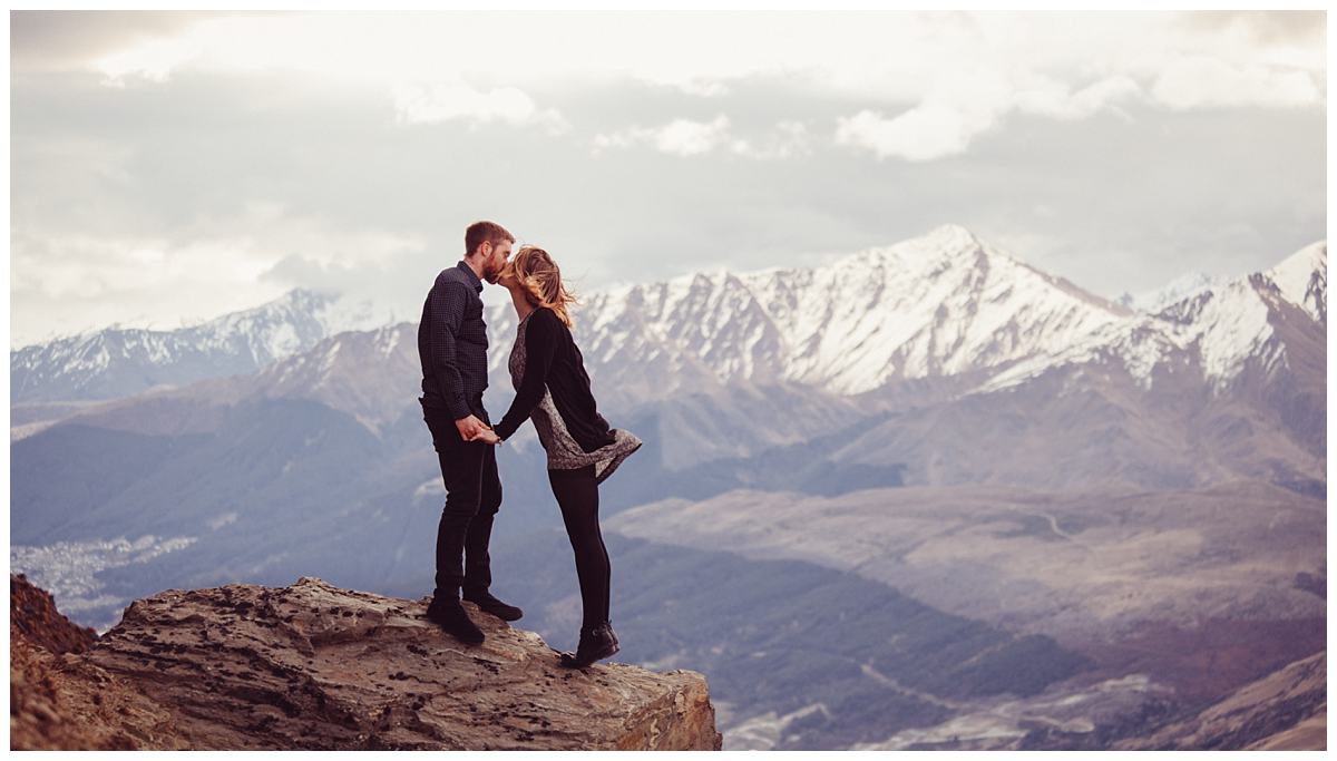 Engagement kiss with snow capped mountains in Queenstown
