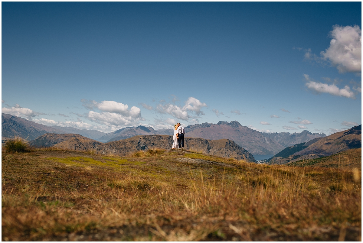 Bride and groom kiss on a hilltop