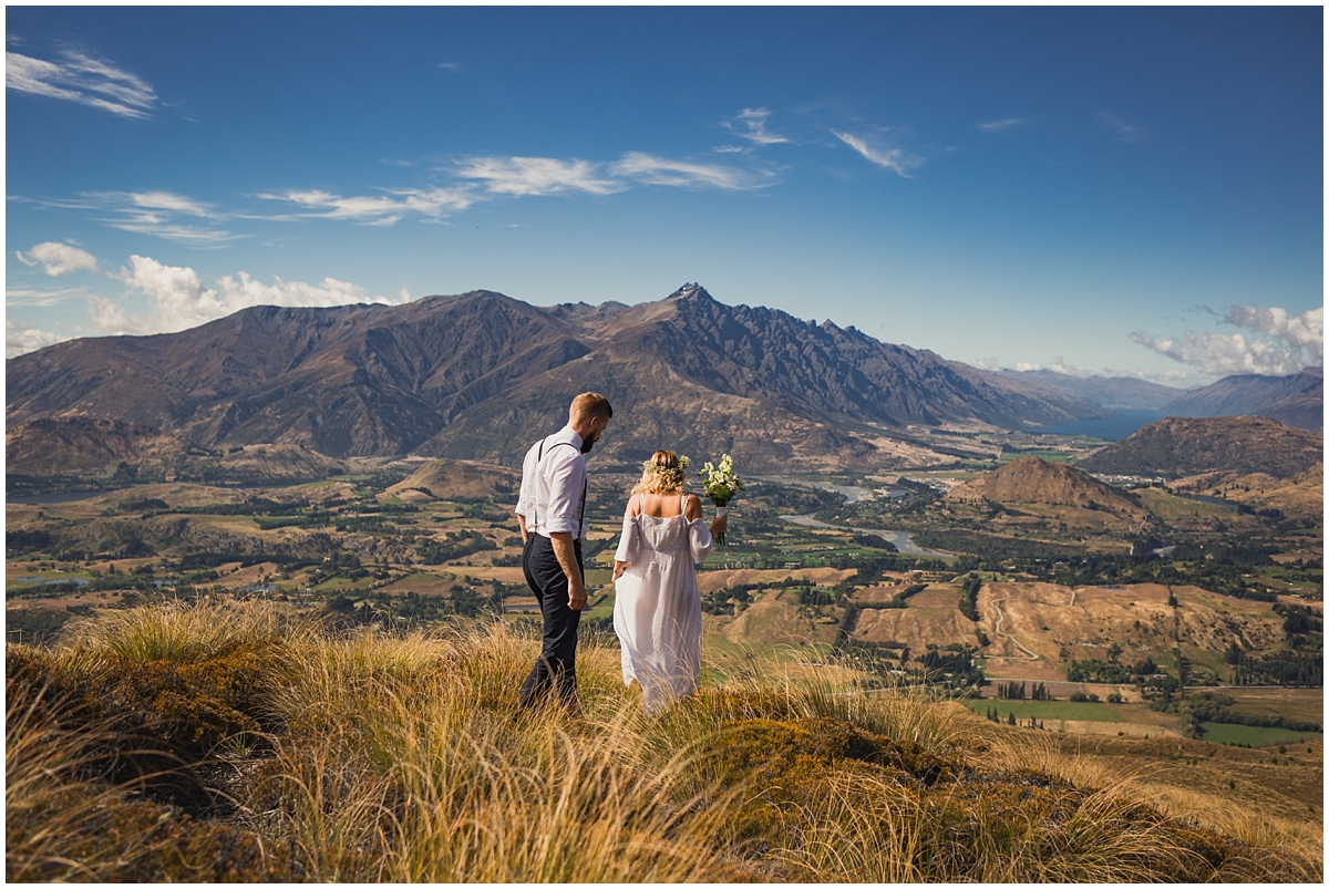 Bride and groom walk across the hillside