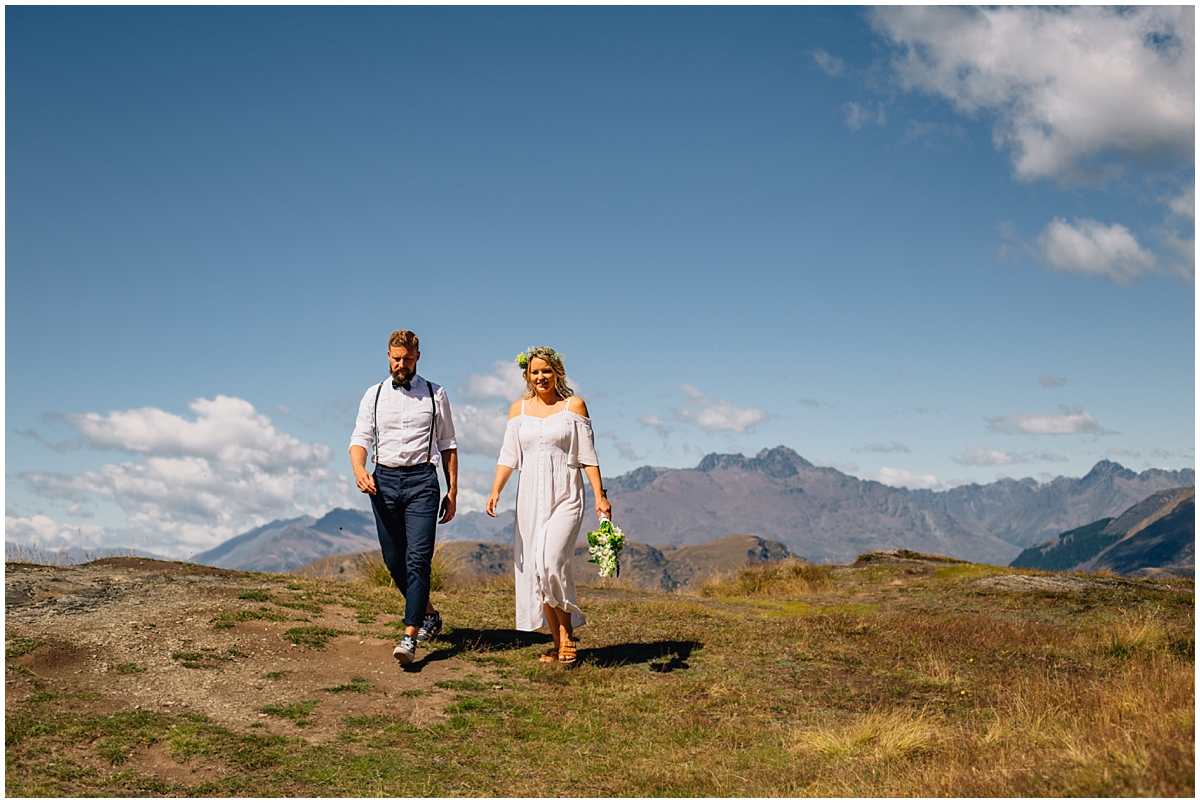 Bride and groom walk across a hilltop