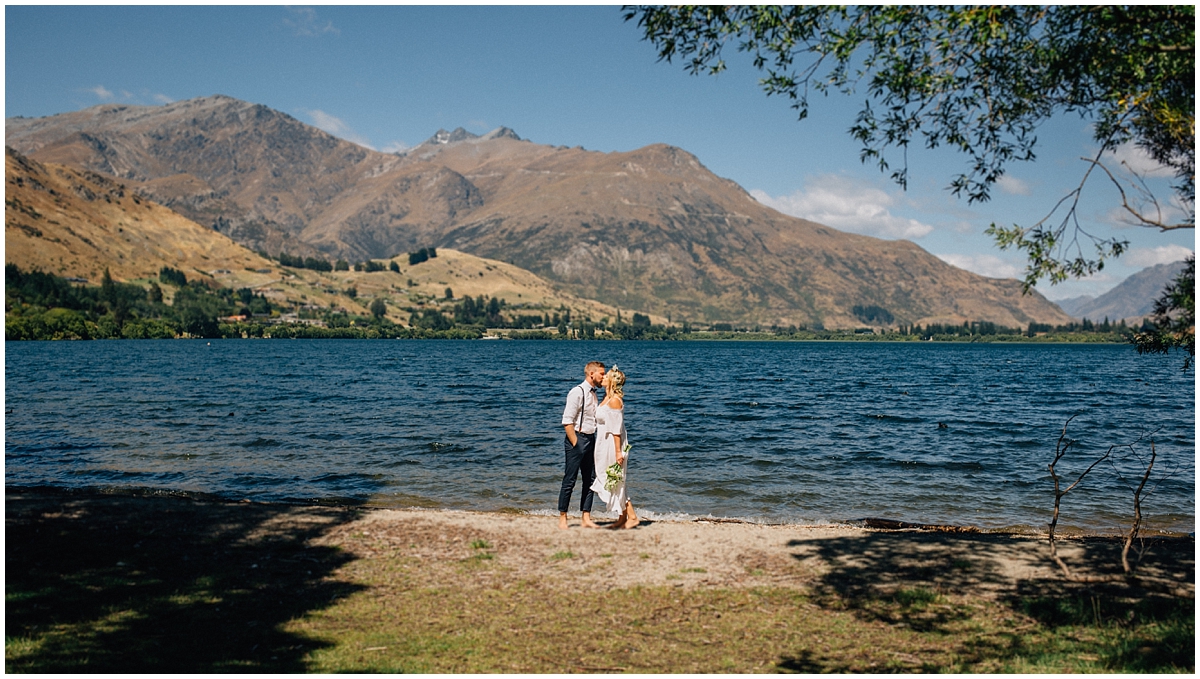 Bride and groom kiss at Lake Hayes