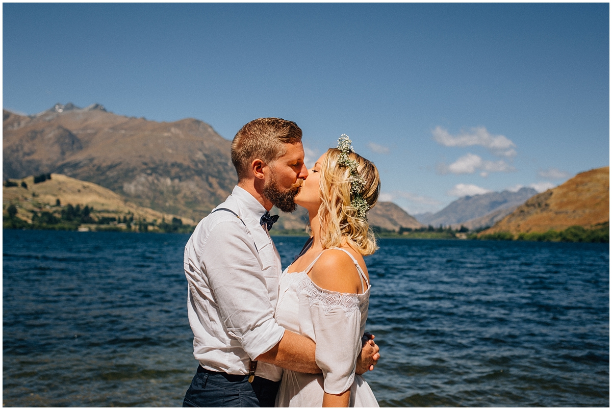 Bride and groom kiss at Lake Hayes