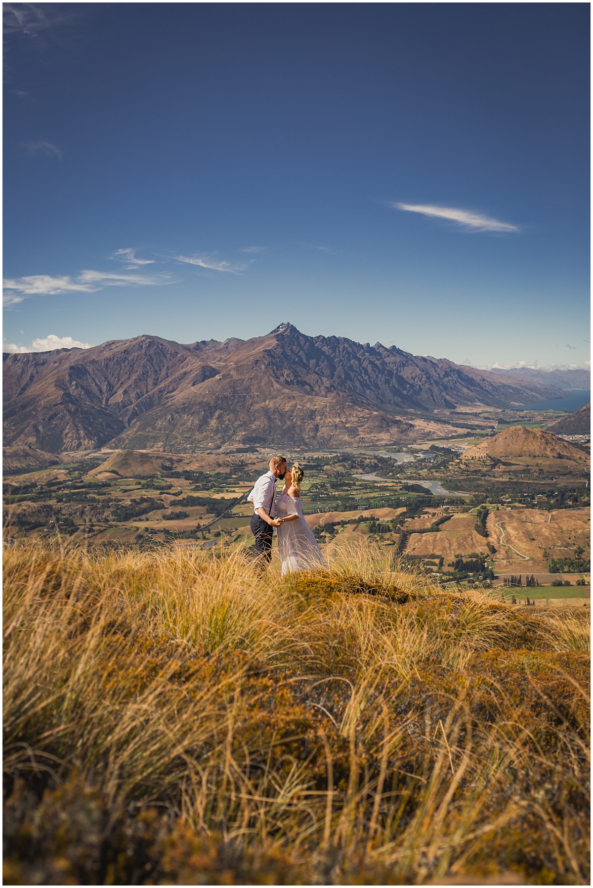 Bride and groom kiss on a hillside