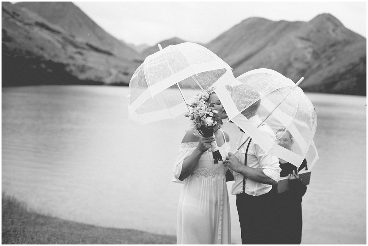 Bride and groom kiss at Moke Lake in the rain