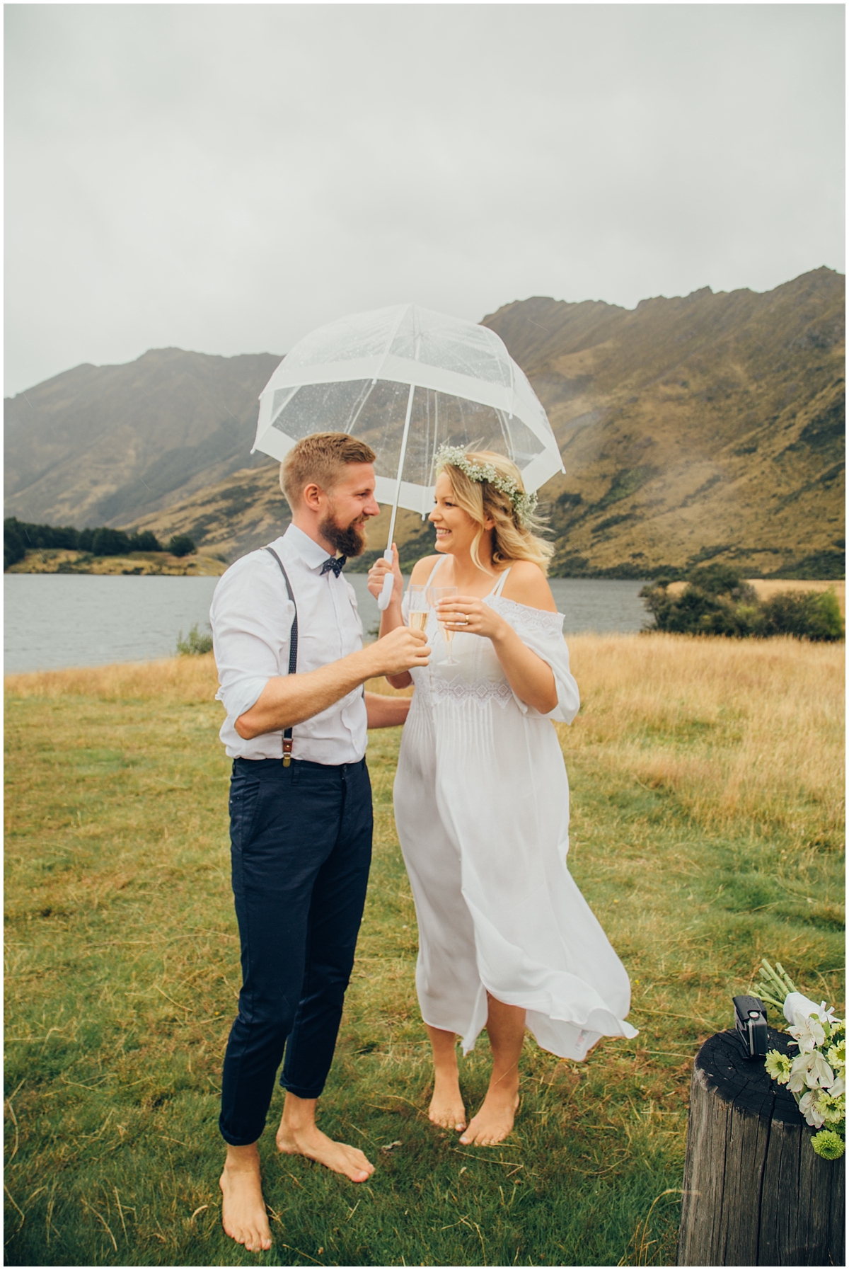 Bride and groom stand under an umbrella in the rain at Queenstown elopement