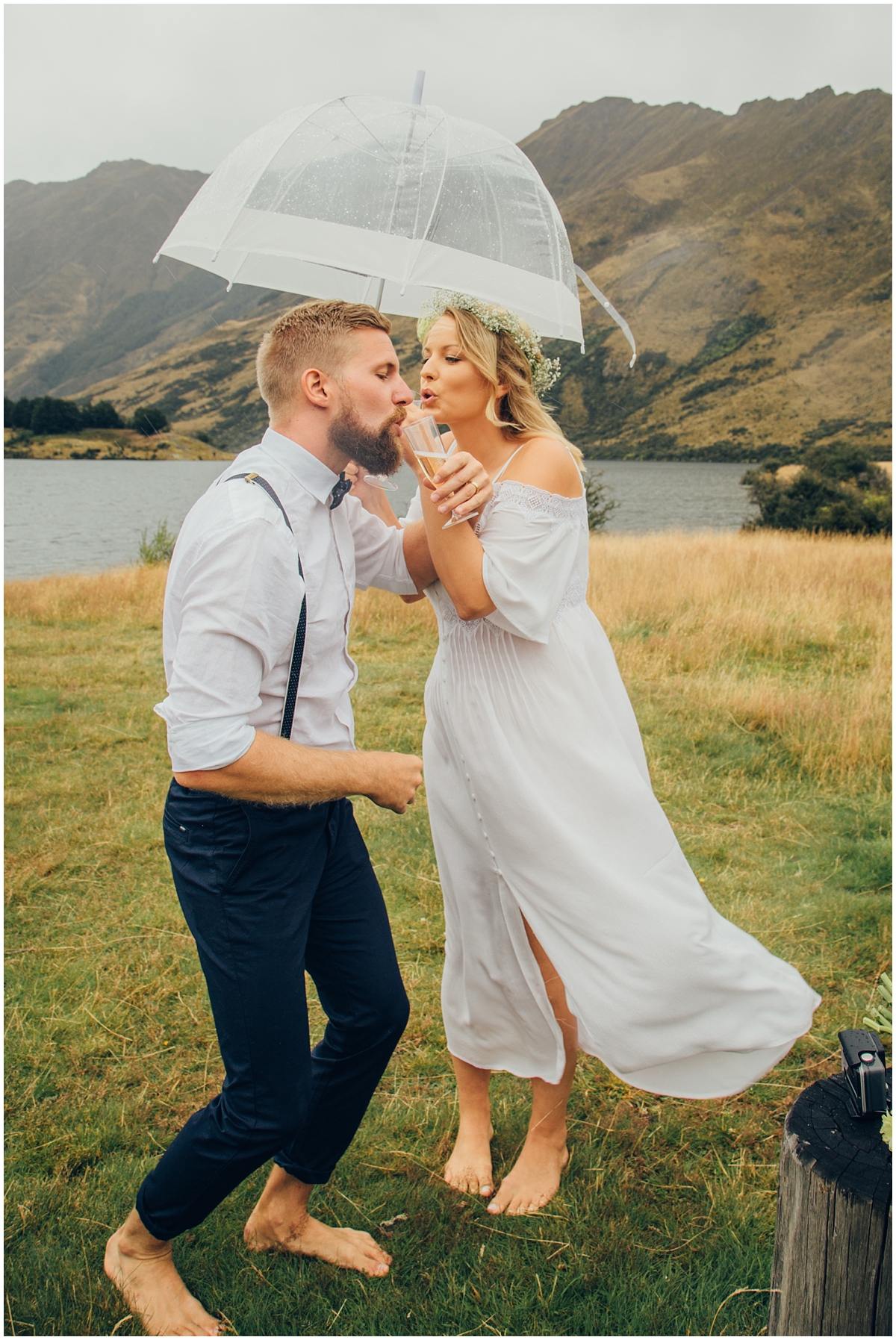 Bride and groom drink champagne under an umbrella
