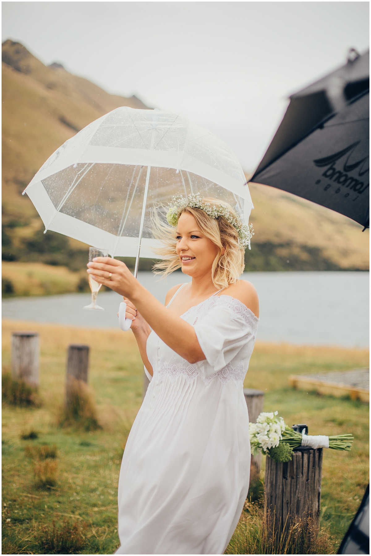 Bride drinks champagne in the rain under an umbrella