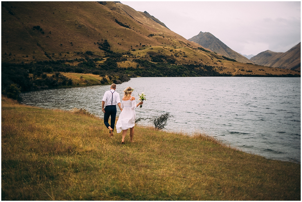 Bride and groom walk around the lake's edge