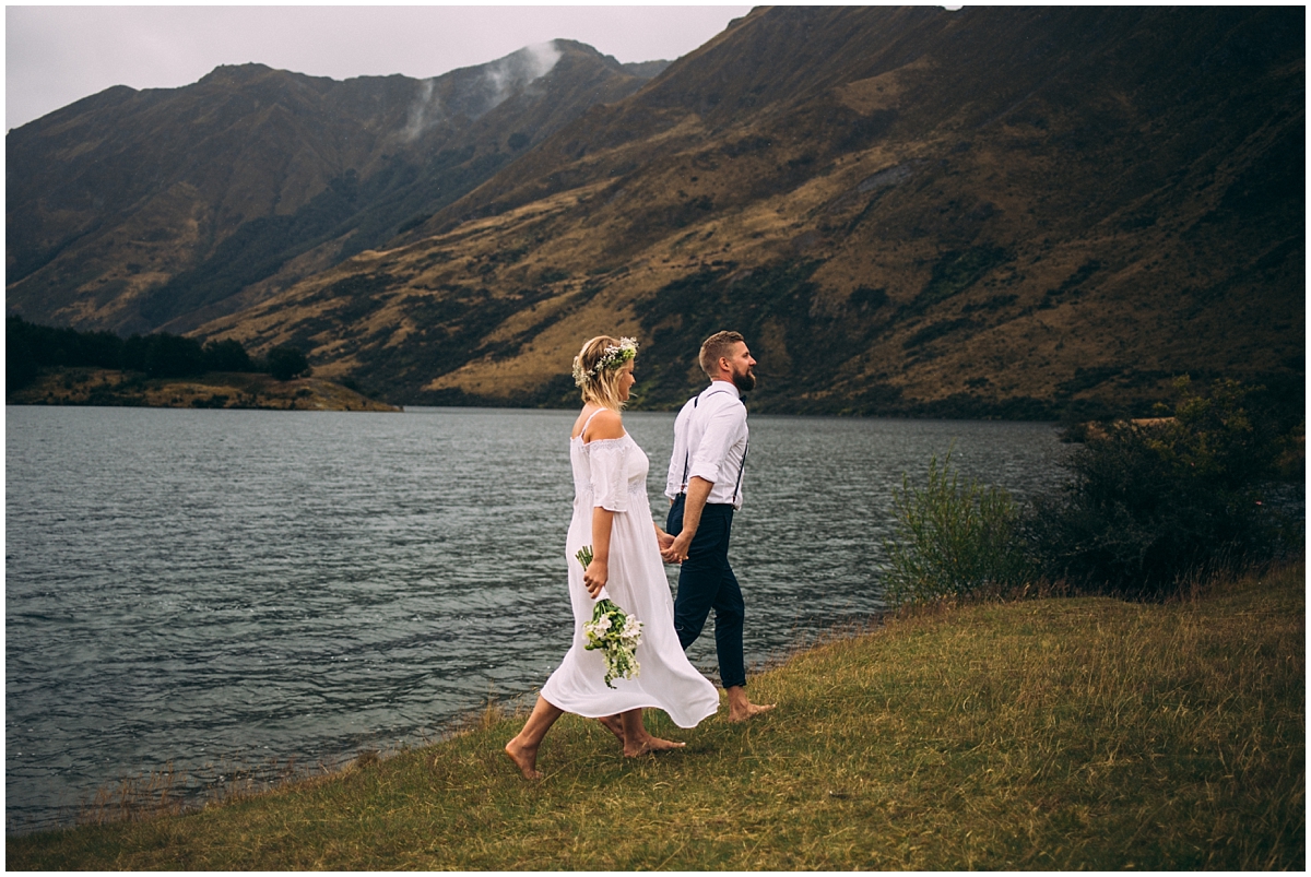 Bride and groom walk along Moke Lake's edge