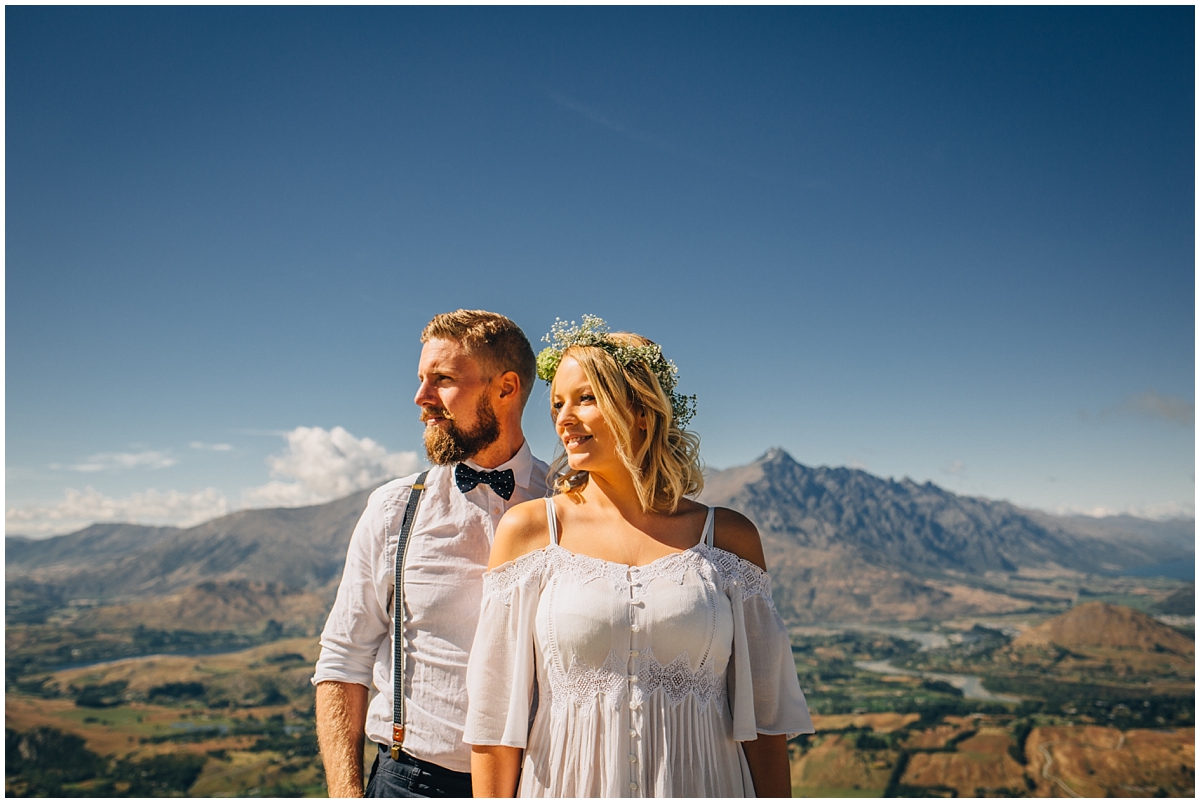 Bride and groom stand together with blue skies and mountain backdrop